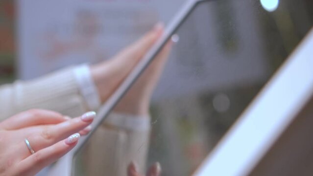 4K Woman using touchscreen terminal in mall. Detail view outstretched female hand touching modern big timetable or info screen in interior.
