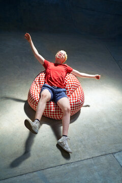 Portrait carefree young man falling back on bean bag chair
