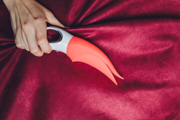 Woman in bedroom holding vibrator in hand.