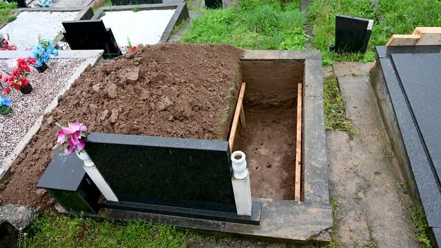 A freshly dug grave in the cemetery. Funeral preparation. Open grave.