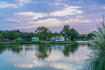 Beautiful views of early morning lakeside recreation, motorhomes camping on the green shore, sport fishing, biking, summer outdoor recreation, authentic sustainability, living in balance with nature