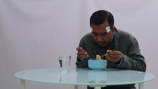 Asian man in jacket shivering while eating boiled noodles on the table