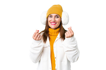 Middle age woman wearing winter muffs over isolated chroma key background making money gesture