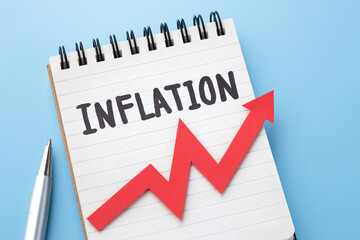 Inflation word on notebook and red graph going up on blue background