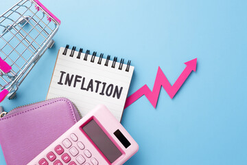 Inflation and consumer price increasing concept with pink purse, calculator and shopping cart on blue background