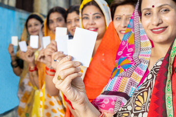 Obraz premium Group of happy traditional indian women wearing sari standing in queue showing blank id card. Mockup.