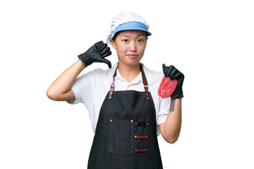 Young caucasian woman wearing an apron and serving fresh cut meat over isolated background showing thumb down with negative expression
