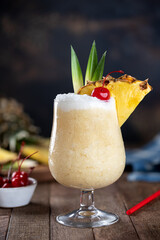 Pina colada cocktail with cherry, pineapple and leaves