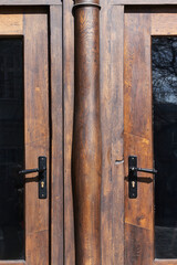Vintage brown wooden door with metal door handles close-up.