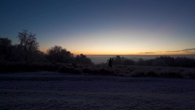 A photographer setting up a camera and tripod in the countryside at dawn