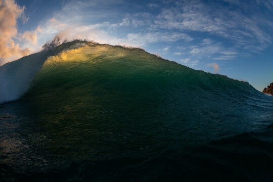 dark and moody wave breaking close up with blue sky background