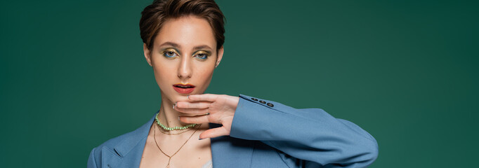 young woman with short hair posing in blue jacket on turquoise green background, banner.