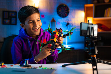 Intelligent indian kid recording social media video for sharing about racing drone at home -...