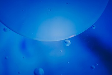 Closeup of blue translucent soap bubbles floating on the water surface, perfect for backgrounds
