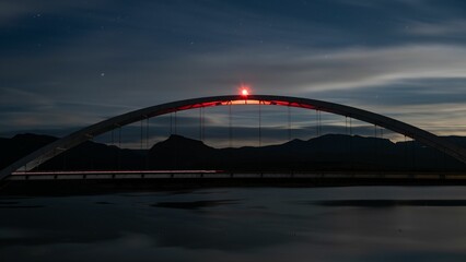 Beautiful nighttime scene of the Theodore Roosevelt Lake Bridge illuminated by a bright light
