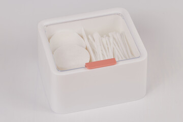 White new plastic organizer for cosmetic products filled with cotton sticks and pads isolated on white background