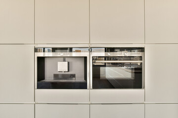 Fototapeta premium two ovens in a kitchen with white cabinets and black counter tops on either side, one has an open door