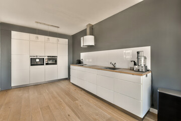 a kitchen with wood flooring and white cabinetd cupboards on the wall behind it is an oven, microwave and dishwasher