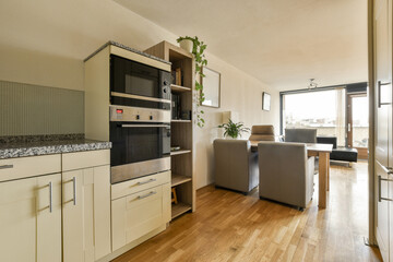 a kitchen and living room in an apartment with wood flooring, white cabinets and black appliances on the wall