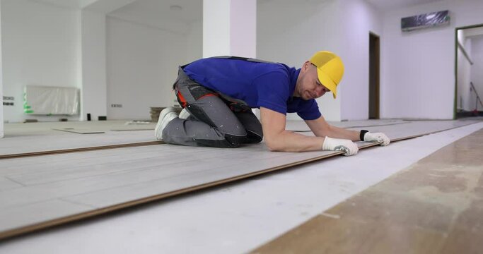 The master checks the laying of the laminate on the floor, close-up. Wooden flooring technology