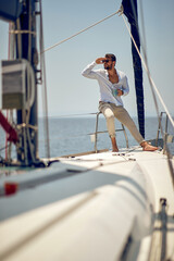 A young handsome male model at a photo shooting on a yacht on the seaside is enjoying the scenery. Summer, sea, vacation