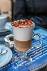 Hot cappuccino coffee with cinnamon powder sprinkled on top in glass cup