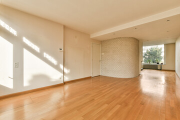 an empty living room with wood floor and white brick wall in the room is very clean, but it's hard to see