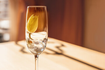 Eine Tischdekoration aus Sektglas und eine gelbe Tulpe.