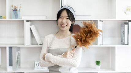 Housewife holding a dusting brush to clean things Pillows, rugs and other things in the living room, Big cleaning, Daily routine ,Removes germs and dirt and deep stains, Clean up on weekends.