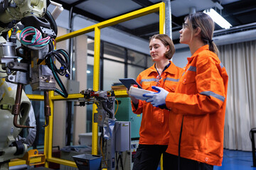 Girl engineer commissioning operating programming and looking at robot machine in the factory