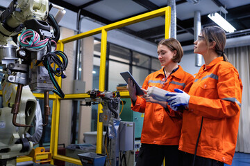 Girl engineer commissioning operating programming and looking at robot machine in the factory