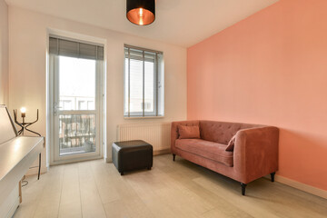 a living room with pink walls and white flooring, an orange couch is in the corner of the room