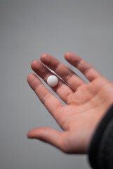 View of hand with white pill on the white background