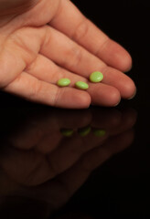 View on three green pills on a hand  on the black background