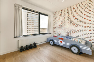 cars is on the wall in this kid's room with wooden flooring and white walls that have been painted