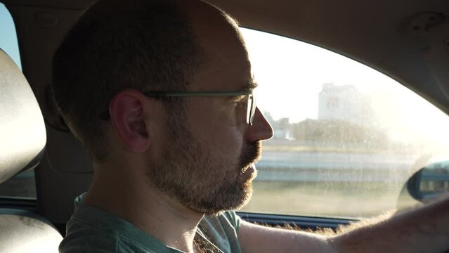 video of contouring detail from co-driver at sunset when the sun is in the way of his eyes while driving, man driving is getting the sun in his eyes