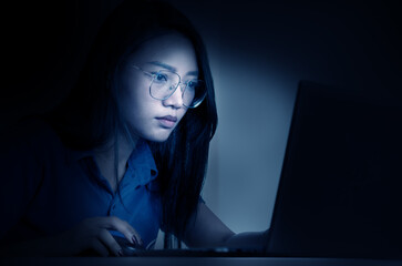 Concentrated young woman working on laptop at night