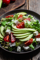 Salad with feta cheese, avocado and tomatoes in a bowl
