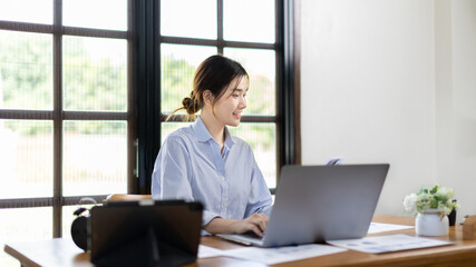 Woman using laptop to work or do homework at home with smiling face in her office, Creating happiness at work with a smile, Live performance or vdo call with laptop, Work from home.