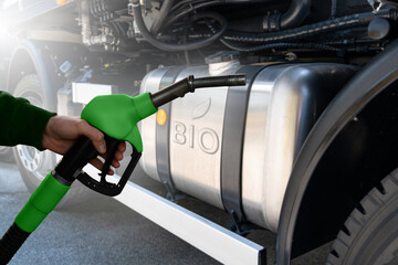 Hand with fuel nozzle on a background of a truck tank 