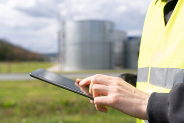 Engineer with digital tablet on a background of gas tanks
