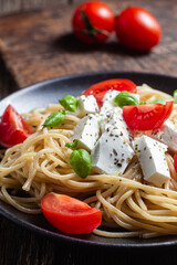 Spaghetti with feta cheese and tomatoes in a plate. Italian pasta