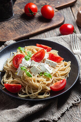 Spaghetti with feta cheese and tomatoes in a plate. Italian pasta