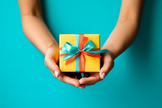 Woman Hands Holding Gift Decorated With Ribbon On Blue Background, Copy Space. Flat Lay, Hands And Present Box, Top View. Valentine Or Love, Spring Holidays, Christmas And Birthday Concept.