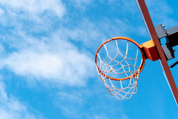 Basketball hoop against a blue sky from a low angle