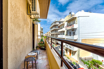 Fototapeta na wymiar Urban landscape from the balcony with table and chairs. Sunny day. Morning coffee with town view. 