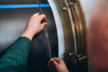 An employee measures the outer diameter of PVC using a tape measure.