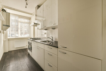 a kitchen with white cabinets and black counter tops on the floor in front of the sink is dark wood floors