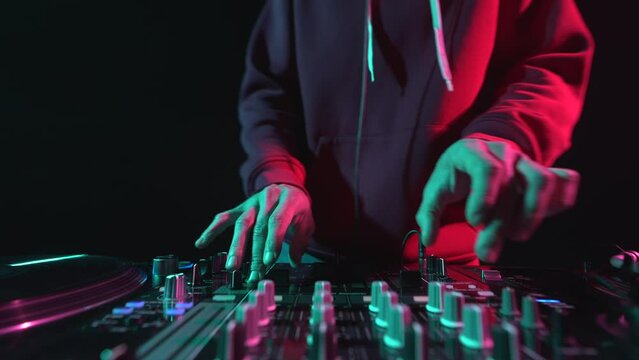 Club DJ playing music on a party. Disc jockey mixing vinyl records on  stage in close up 4K video clip
