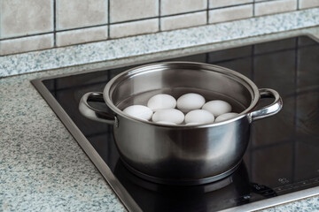 Eggs are boiled in a steel pan on an electric stove